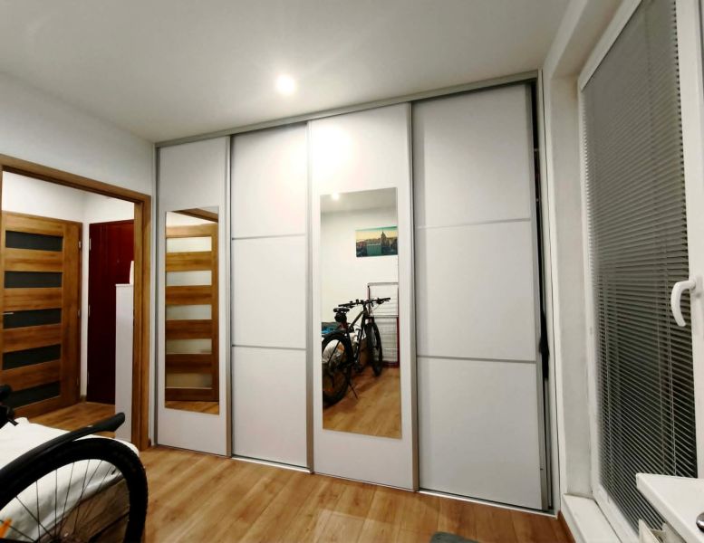 Schlafzimmer mit Schrank und Fahrrädern in einer 3-Zimmer-Wohnung; Boden mit Holzdekor.