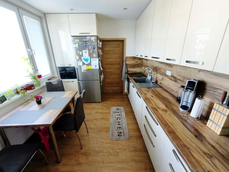 Küche in einer 3-Zimmer-Wohnung mit Holzboden, Tisch und moderner Ausstattung.