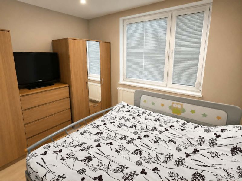 Schlafzimmer in einer 3-Zimmer-Wohnung mit Möbeln in Holzdekor und Fernseher.