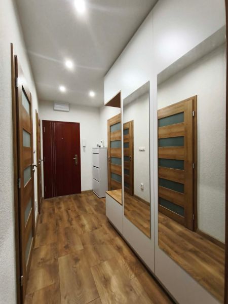 Ein Flur mit Spiegeln, Holztüren und einem Boden mit Holzdekor in einer 3-Zimmer-Wohnung.
