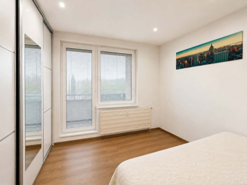 Schlafzimmer in einer 3-Zimmer-Wohnung mit Bett, Einbauschrank und Boden mit Holzdekor.