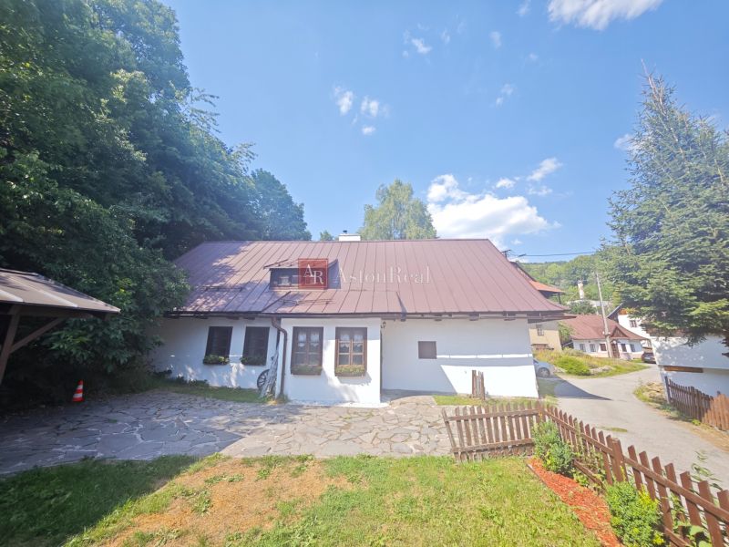 Eine Hütte in Špania Dolina, umgeben von Natur, mit einem steinernen Weg und einem Holzzaun.