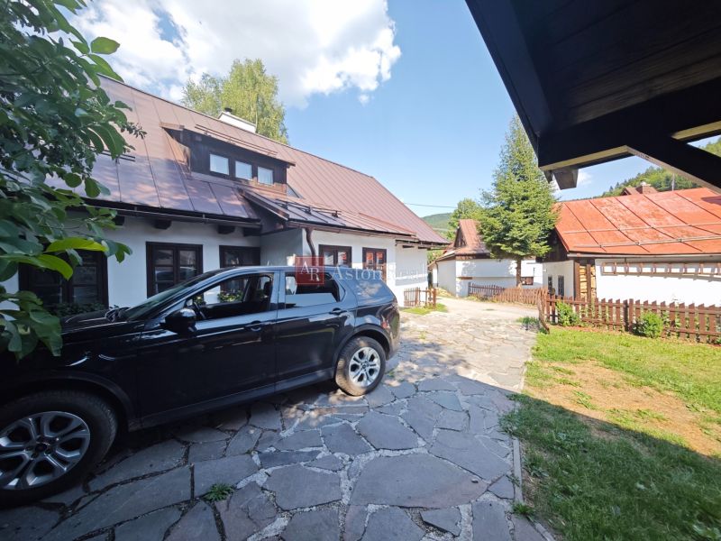 Ein Auto, das bei einer Hütte in Špania Dolina geparkt ist, mit sichtbaren Dächern und einem Zaun.