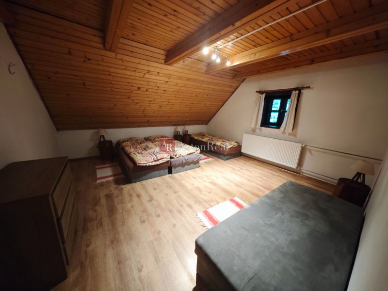 Ein Zimmer mit drei Betten, einem Boden in Holzoptik und einer schrägen Holzdecke in einer Hütte.