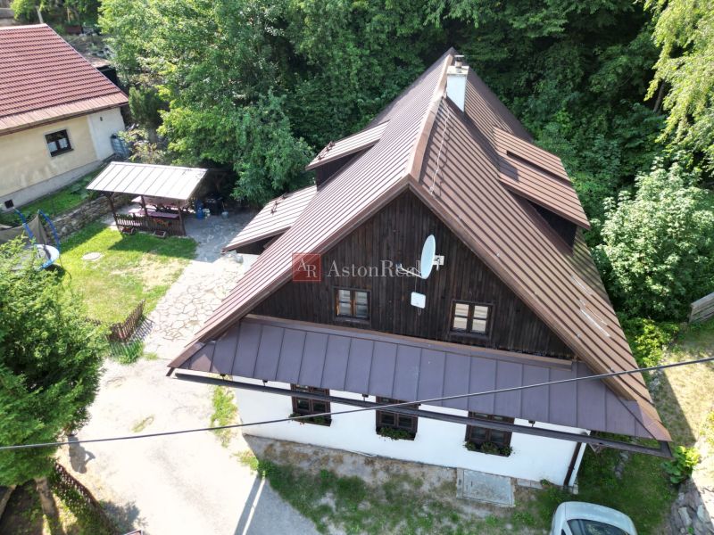 Ein Einfamilienhaus in Špania Dolina mit Holzverkleidung und einer Umgebung voller Grün.