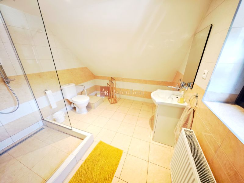 Helles Badezimmer in einer Hütte mit Badewanne und Waschbecken, ergänzt durch helle Fliesen.