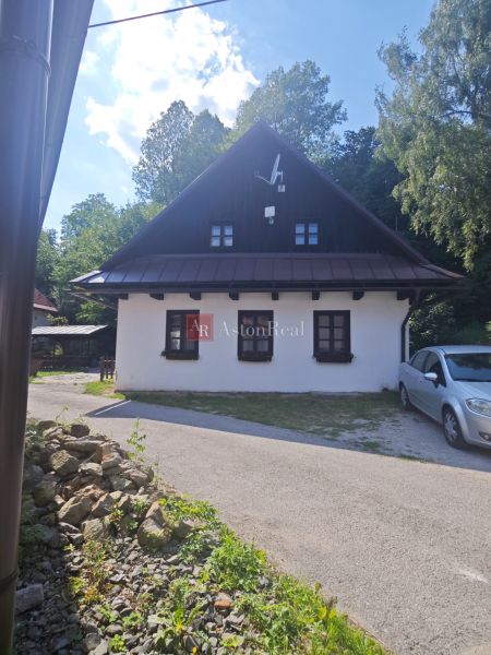 Ein Ferienhaus in Špania Dolina mit weißer Fassade und Satellitenschüssel, umgeben von Grün.