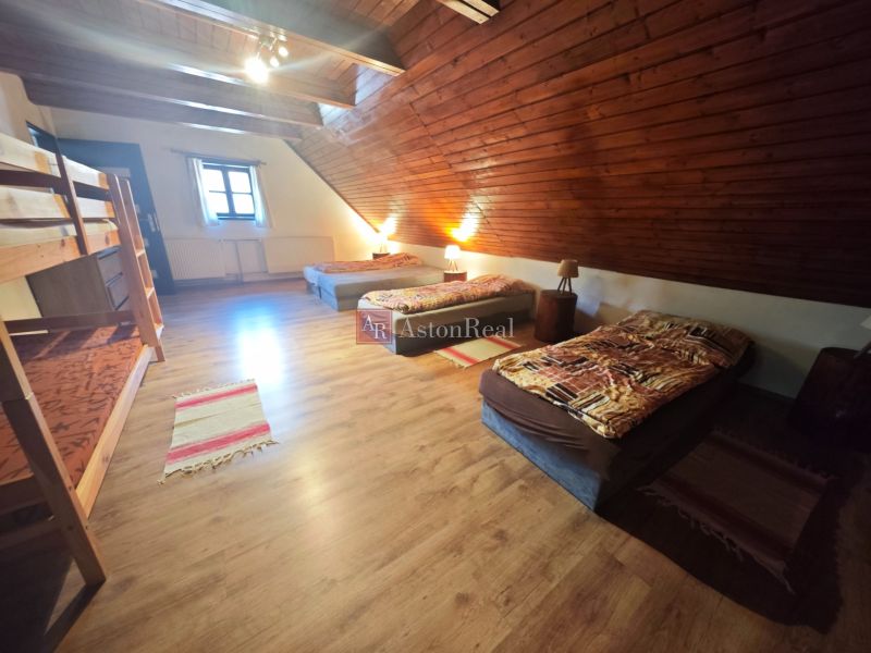Ein Dachzimmer in einer Hütte mit einem Boden in Holzoptik und mehreren Betten.