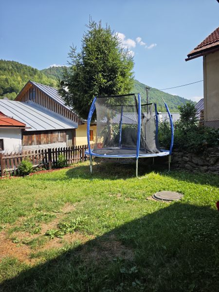 Trampolin bei der Hütte in Špania Dolina, umgeben von Gras und Bäumen im Hintergrund.