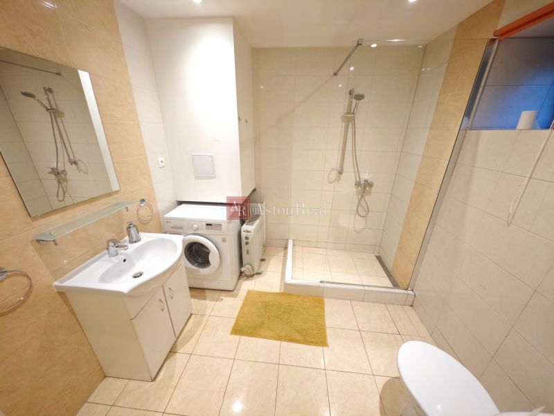 Badezimmer in der Hütte mit Waschmaschine, Duschkabine und Boden mit Holzdekor.