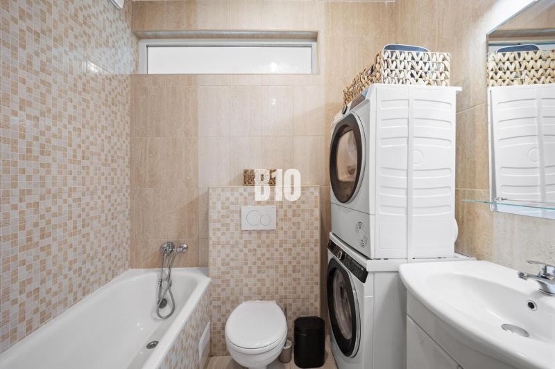 Badezimmer in einer 2-Zimmer-Wohnung mit Waschmaschine, Trockner, Badewanne und Toilette.