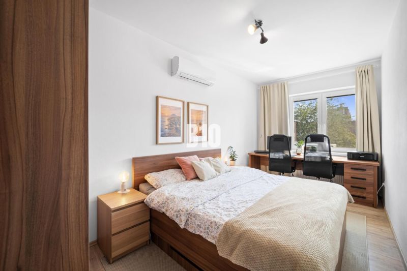 Schlafzimmer in einer 2-Zimmer-Wohnung mit Holzboden und Schreibtisch.