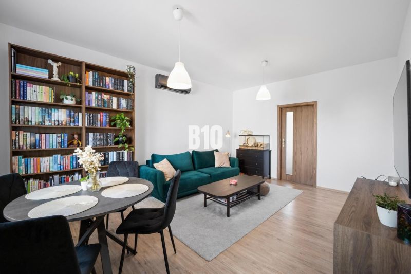 Wohnzimmer in einer Zweizimmerwohnung mit Holzdekorboden und Bücherregal.