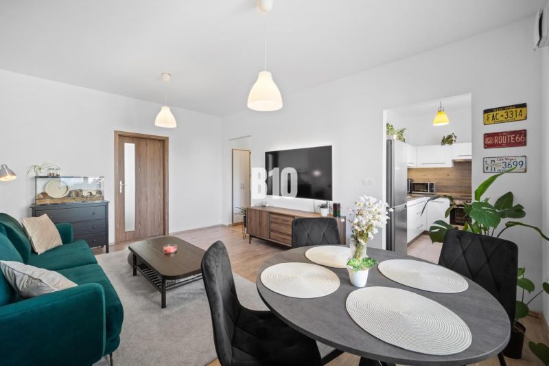 Wohnzimmer in einer Zweizimmerwohnung mit Holzboden und Esstisch.