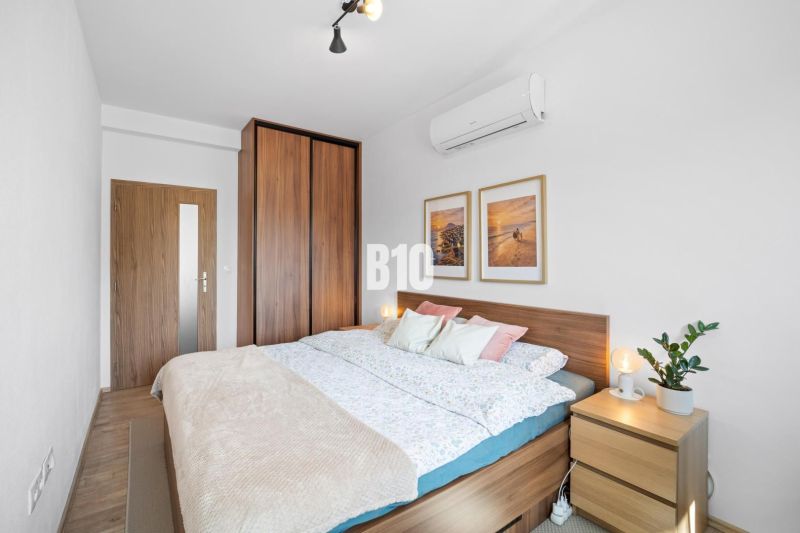 Schlafzimmer mit Bett, Kommode und Holzboden in einer 2-Zimmer-Wohnung.