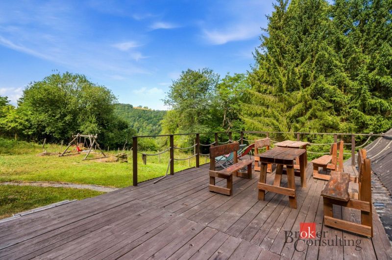 Eine Hütte in Píla mit einer Holzterrasse, Holzmöbeln und Blick auf Bäume und eine Schaukel.