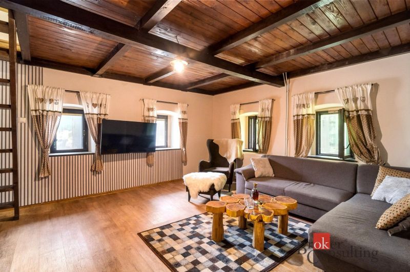 Wohnzimmer in der Hütte mit Holzboden und bequemen Sitzgelegenheiten.