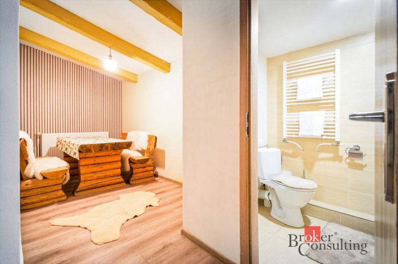 Eine Hütte mit Holzmöbeln und einem Boden in Holzoptik, nebenan ein Badezimmer.