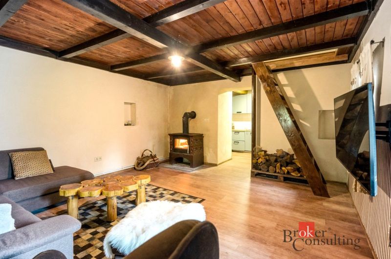 Innenraum einer Hütte mit einer Holzträgerdecke, einem Ofen und einem Boden mit Holzdekor.