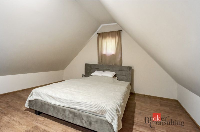 Dachbodenschlafzimmer in der Hütte mit einem Bett und einem Boden in Holzoptik.