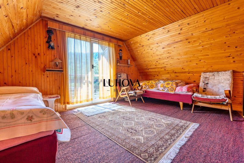 Ein Zimmer in einer Hütte mit Holzverkleidung, einem Bett, einem Sessel und einem Teppich auf dem Boden.