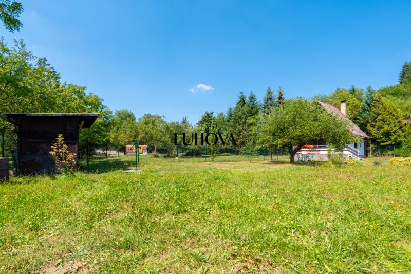 Die Hütte auf Dubková in Lazy pod Makytou, umgeben von grünen Bäumen und Rasen.