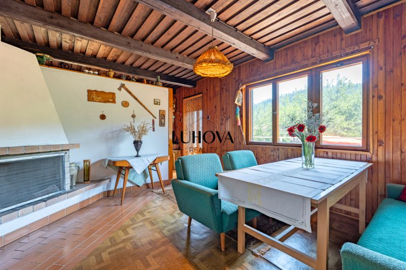 Das Innere der Hütte mit Holzelementen, Kamin und Blumen auf dem Tisch wirkt gemütlich.