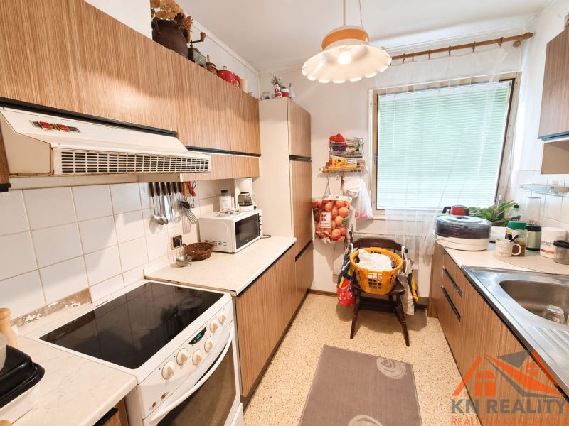 Die Küche im Einfamilienhaus hat einfache Möbel mit Holzdekor und weiße Elektrogeräte.