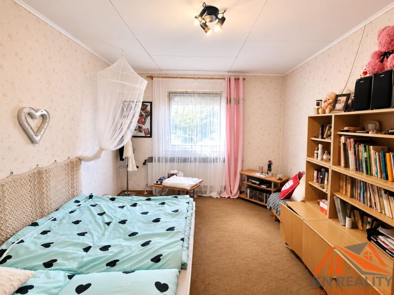 Izba eines Familienhauses mit Bett, Bücherregal und bunten Accessoires.