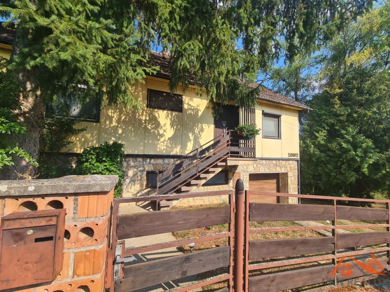 Ein Einfamilienhaus in Svodín mit Treppe, Umzäunung und dichter Vegetation rundherum.