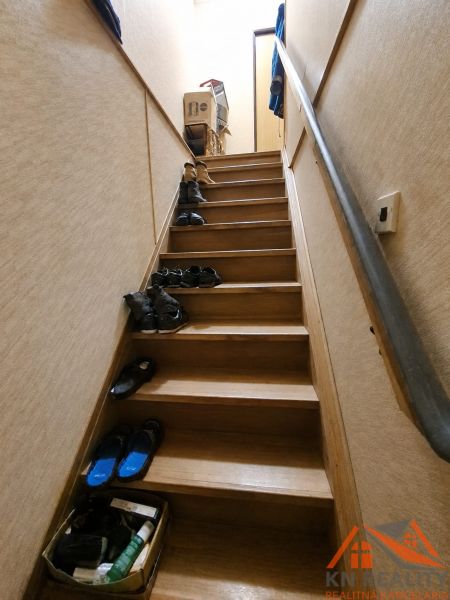 Eine Treppe mit einem Boden in Holzoptik voller Schuhe in einem Einfamilienhaus.