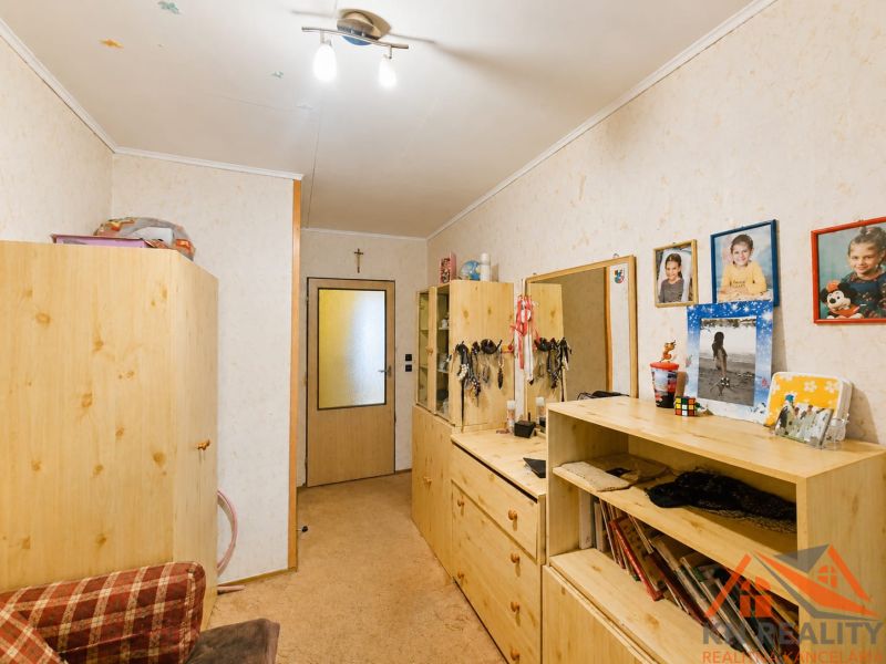Innenraum eines Einfamilienhauses mit Holzmöbeln, Teppich und Fotos an der Wand.