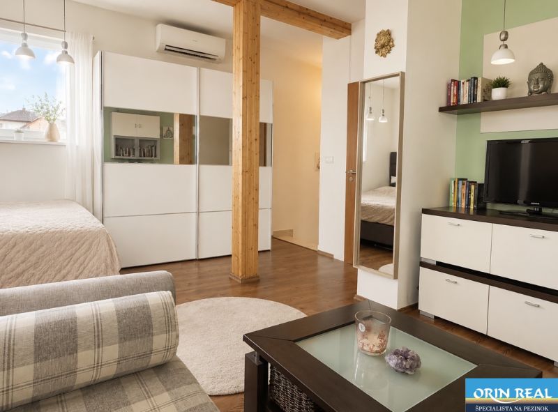 Wohnraum in einer Einzimmerwohnung mit Holzboden und modernen Möbeln.