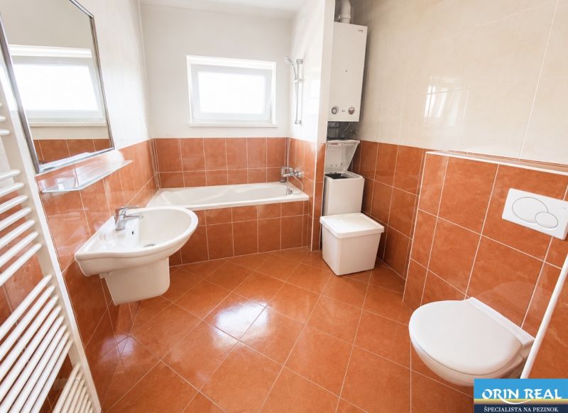 Badezimmer mit Badewanne, Waschbecken, Toilette und Waschmaschine in einer Einzimmerwohnung.