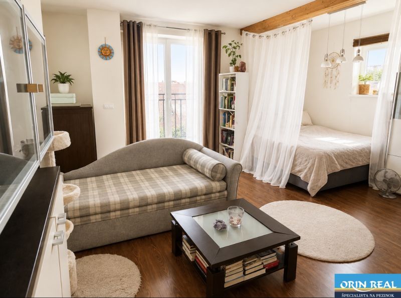 Heller Wohnbereich in einer Einzimmerwohnung mit Holzboden und bequemen Sofa.