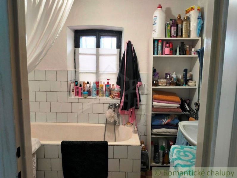 Badezimmer in einem Einfamilienhaus mit Badewanne, Regalen und verschiedenen Toilettenartikeln.