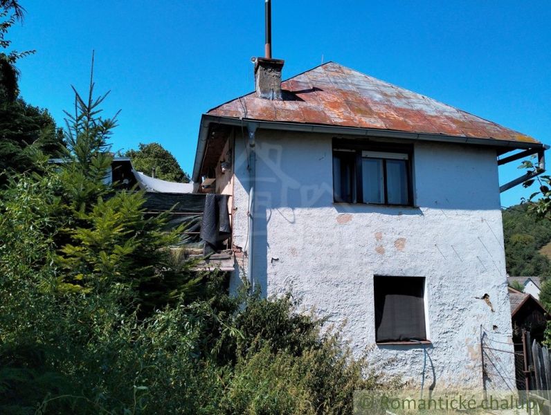 Ein Einfamilienhaus in Stará Turá mit einem abgenutzten Dach und überwucherter Umgebung.