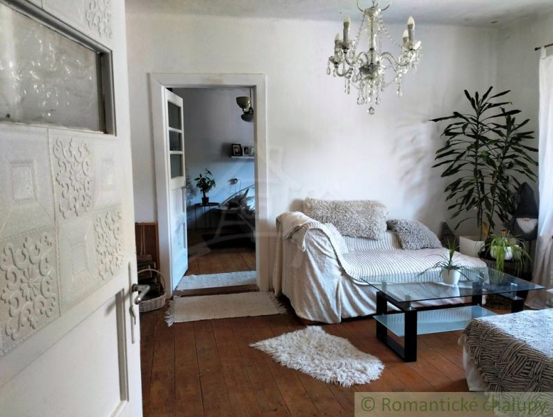 Wohnzimmer in einem Einfamilienhaus mit Sofa und Kronleuchter, Boden mit Holzdekor.