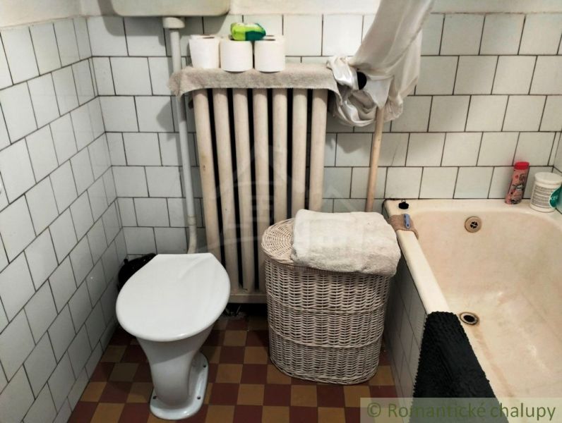 Ein Badezimmer in einem Einfamilienhaus mit Badewanne, Toilette, Heizkörper und Aufbewahrungskorb.