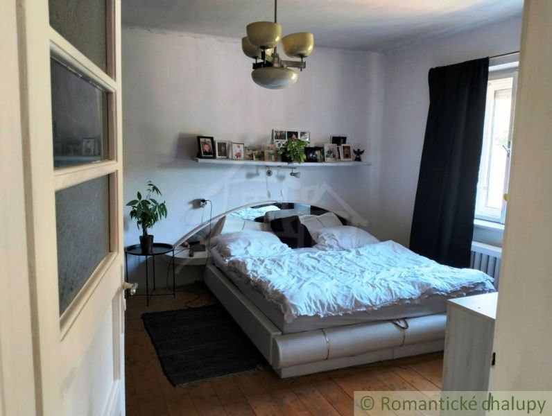 Schlafzimmer mit Doppelbett, Pflanze und Holzboden in einem Einfamilienhaus.