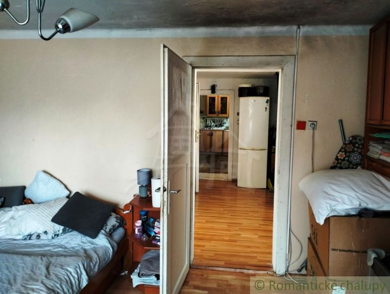 Innenraum eines Einfamilienhauses mit Bett und Blick auf die Küche durch offene Türen.