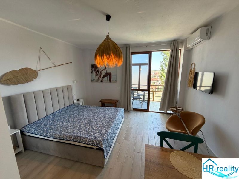 Einzimmerwohnung mit Bett, Holzboden und Terrasse bietet Aussicht.