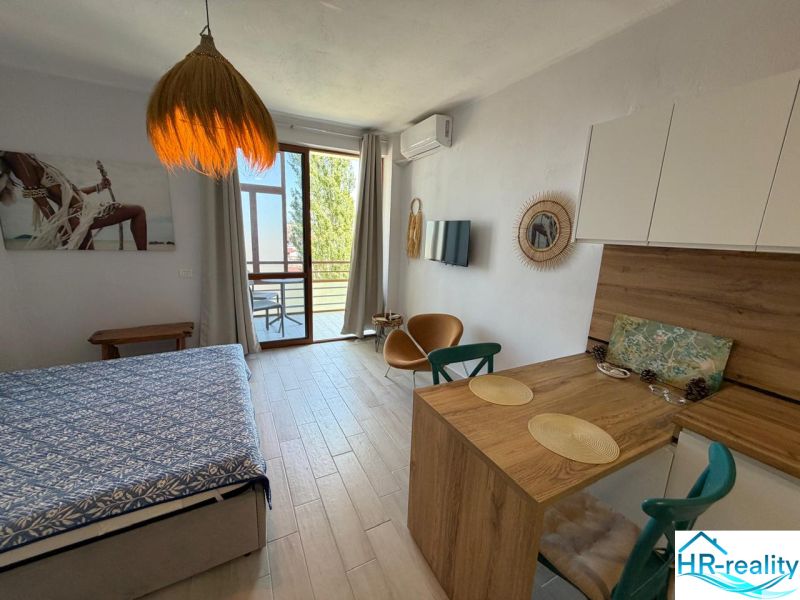 Ein Studio-Apartment mit Holzboden, hellem Interieur und Balkon für Komfort.