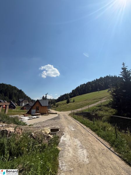 Freizeitgrundstücke in Litmanová mit Wald- und Hausszenerie, blauer Himmel.