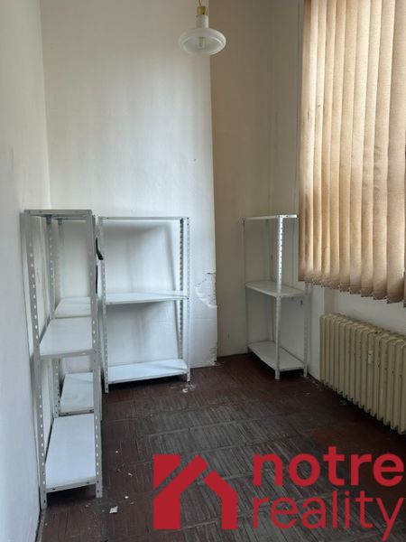 Ein Büro mit Regalen, einem Heizkörper und Vorhängen, ein Boden mit Holzdekor.