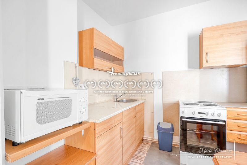 Küche in einer Einzimmerwohnung mit Holzdekor und weißer Mikrowelle.