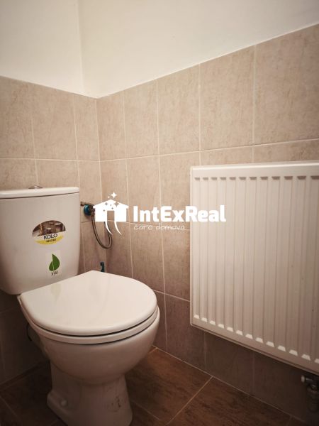 Toilette in Geschäftsräumen mit Fliesen und Heizkörper.