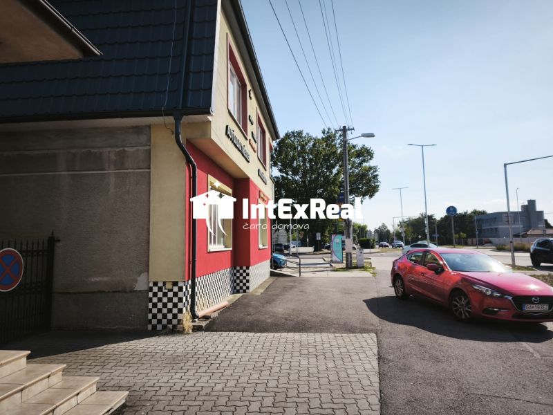 Geschäftsräume in der Straße SNP in Šaľa mit einem roten Auto auf der Straße.