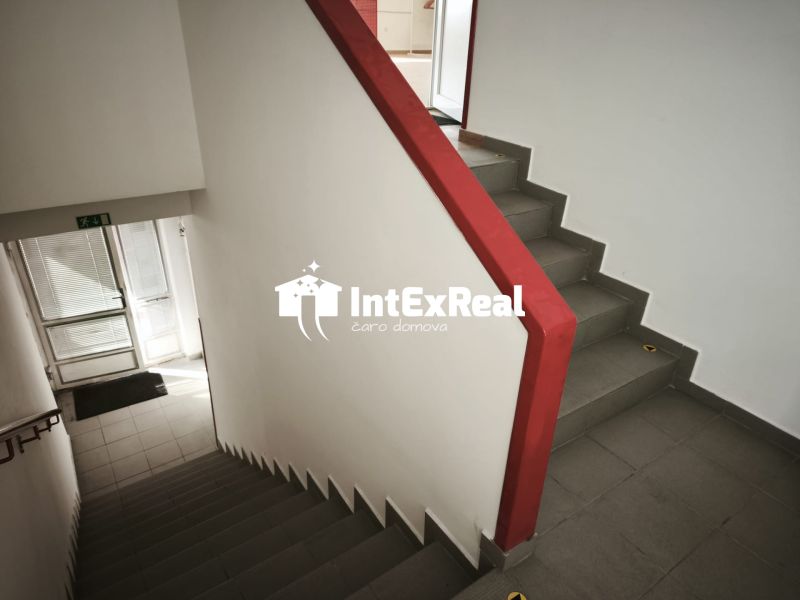 Eine Treppe mit einem roten Geländer in Geschäftsräumen, Boden mit Fliesen.