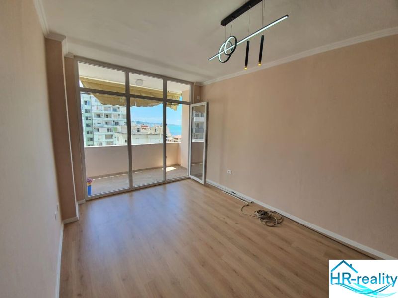 Ferienwohnung mit Glaswand und Boden in Holzoptik, Zugang zum Balkon.